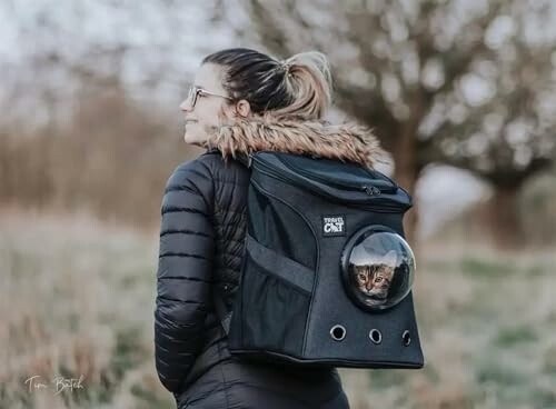 Woman carrying a cat in a backpack with a clear bubble window.